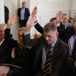 Kilka osób trzyma rękę w górze podczas głosowania