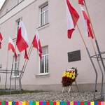 Ul. Mazowiecka - tablica upamiętniająca Ryszarda Kaczorowskiego - ostatniego Prezydenta RP na uchodźstwie - pod nią wieniec, obok biało-czerwone flagi.