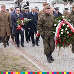 Cmenatrz Św. Rocha - za żołnierzem z biało-czerwonym wieńcem idą z kwiatami w rękach marszałek województwa, wojewoda podlaski, przewodniczący sejmiku i żołnierze