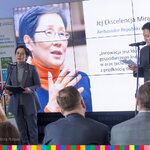 Ambasador Korei podczas przemówienia przy mikrofonie, za nią przy mównicy podczas przemówienia, w tle ekran z jej zdjęciem i cytatem wypowiedzi
