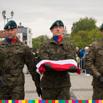 Trzech żołnierzy niesie flagę RP do uroczystego podniesienia