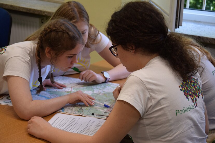Czwórka dziewczyn w koszulce z logo województwa podczas analizy mapy