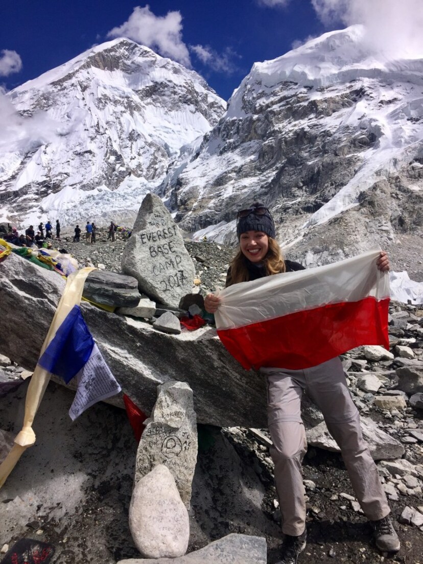 Podróżniczka prezentuje flagę Polski na tle gór.