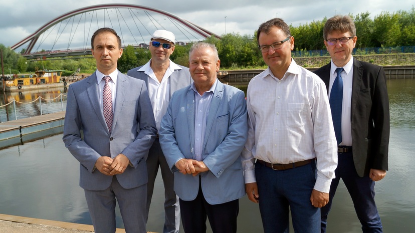 Członkowie spotkania na grupowym zdjęciu na tle Narwii i mostu w Ostrołęce