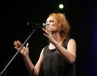 Rudowłosa kobieta przy mikrofonie podczas wykonywania piosenki