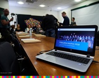 Laptop stojący na stole z wyświetloną grafiką z laureatami Podlaskiej Marki
