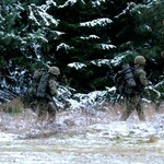 Trzech żołnierzy idzie obok drzew pokrytych śniegiem
