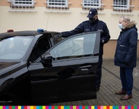 Policjant wraz z wicemarszałkiem Olbrysiem stoją przy czarnym samochodzie osobowym