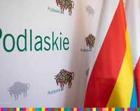 Ścianka promocyjna z napisem Podlaskie i logo województwa - żubrami. Na tym tle flagi - województwa i Polski.