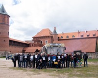 Zdjęcie grupowe osób na tle autobusu i zamku w Tykocinie