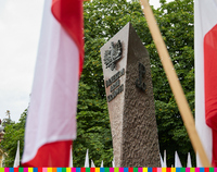 Pomnik Żołnierzy Armii Krajowej wyłaniający się między flagami biało-czerwonymi