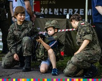 Dwóch żołnierzy pokazuje dziecku obsługę broni