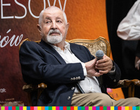 Janusz Majewski siedzi na krześle, w ręku trzyma mikrofon