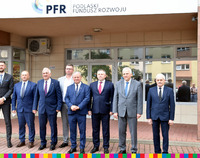 Osiem mężczyzn ubranych elegancko stoi przed budynkiem