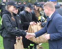 Marek Malinowski, członek zarządu podaje rękę strażakom