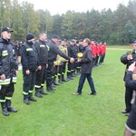 Mężczyzna podaje rękę strażakowi, który stoi z innymi w szeregu