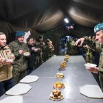 Żołnierze i para prezydencka podczas spożywania posiłku w namiocie wojskowym.