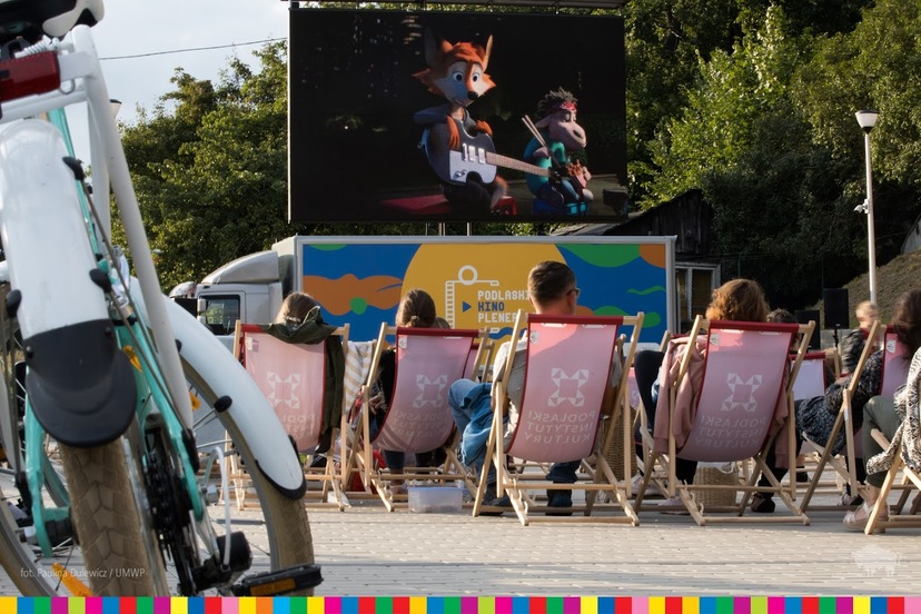 ludzie siedzący na leżakach oglądają film w ramach Podlaskiego Kina Plenerowego