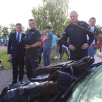 Marek Malinowski stoi z policjantami. W tle tłum osób