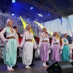 Kobiety ubrane w stroje folkowe tańczą na scenie 