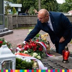 Sekretarz Województwa układa wstęgę przy kwiatach na pomniku ks. St. Suchowolca.