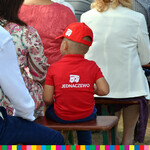 Chłopczyk ubrany w czerwoną czapkę z daszkiem i koszulkę z napisem: 