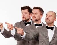 na zdjęciu trzech mężczyzn z grupy Fair Play Crew stoją jeden za drugim ubrani w jasne garnitury i muszki i wszyscy trzej wskazują palcem w jednym kierunku