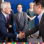 Minister wita się - ściskając dłoń - z prezesem Samsung Electronics Polska, w tle ambasador Korei 