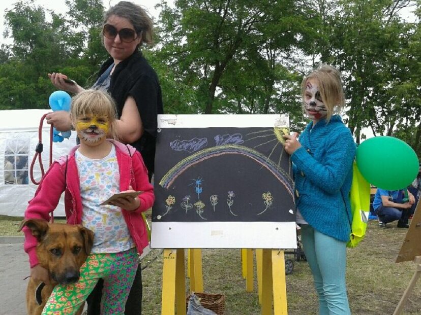 Dzieci z pomalowanymi twarzami na pikniku , przy sztalugach z rysunkiem