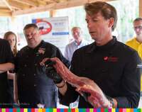 Karol Okrasa prezentuje sztukę mięsa, w tle uczestnicy warsztatów kulinarnych