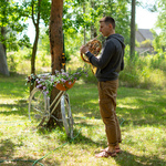 Uczestnik gra na instrumencie w lesie przy koszu kwiatów i ziół