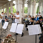 Koncert w Stacji Białowieża Pałac - na pierwszym planie pulpity z nutami w tle dyrygent i muzycy