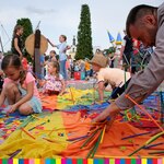 Grupa dzieci i dorosłych układa konstrukcje z kolorowych rurek