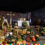 Scena dożynkowa przystrojona wieńcami i płodami rolnymi, na której celebrowana jest msza święta. 