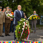 Sekretarz Województwa Tomasz Szeweluk składający wieniec z białych i czerwonych róż.