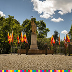 Żołnierze pełniący  wartę przy pomniku. Obok pomnika znajdują się flagi w kolorach biało-żółto-czerwonym.