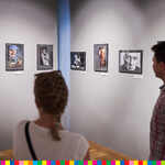Dwie osoby oglądające wiszącą na ścianie ekspozycję zdjęć