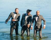 Trzech mężczyzn w garniturach stojących po kolana w wodzie