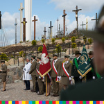 Grupa osób w mundurach ze sztandarami na wzgórza z krzyżami