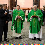 Przemawiający mężczyzna stoi obok dwóch księży.