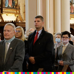 W środku widoczny minister Dariusz Piontkowski w otoczeniu wiernych uczestniczący w uroczystej Mszy Świętej 