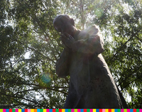 Pomnik księdza Jerzego ze złożonymi dłońmi wśród drzew.