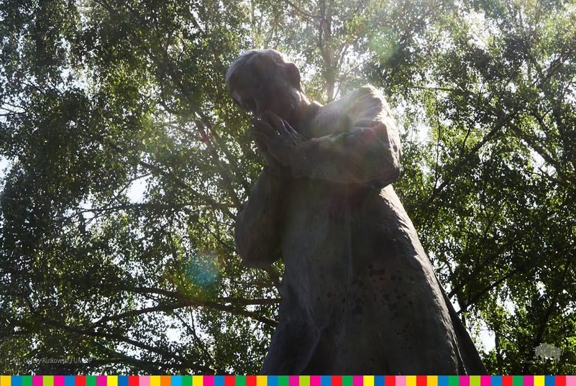 Pomnik księdza Jerzego ze złożonymi dłońmi wśród drzew.