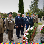 Marszałek Artur Kosicki i wojewoda podlaski w asyscie przedstawicieli służb mundurowychstoją przed Grobem Nieznanego Sybiraka.