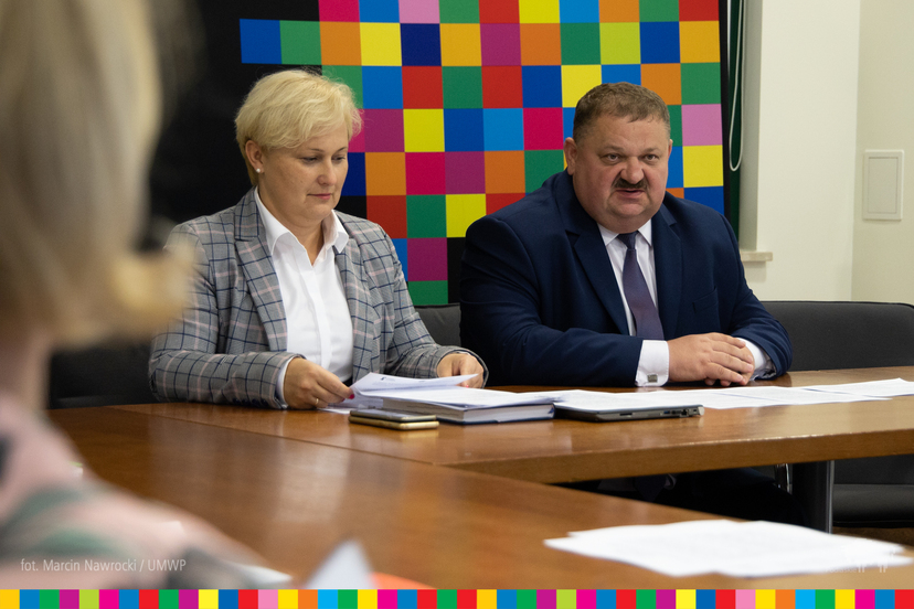 Stanisław Derehajło, Wicemarszałek Województwa Podlaskiego i Agnieszka Aleksiejczku, Dyrektor Departamentu Społeczeństwa Informacyjnego UMWP siedzą przy stole z dokumentami.