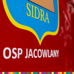 Napis na wozie strażackim OSP Jacowlany z fragmentem herbu gminy Sidra