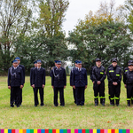 Strażacy OSP Jacowlany stoją obok siebie w szeregu. Jedni są ubrani w mundury galowe, drudzy w kombinezony i kaski