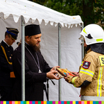 Prawosławny kapłan przekazuje strażakowi OSP drewnianą ikonę prawosławną. 