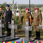 Przedstawiciele służb mundurowych stoją przy mogiłach żołnierskich.