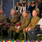 Siedzą uczestnicy uroczystości, w tym mężczyźni w mundurach wojskowych.